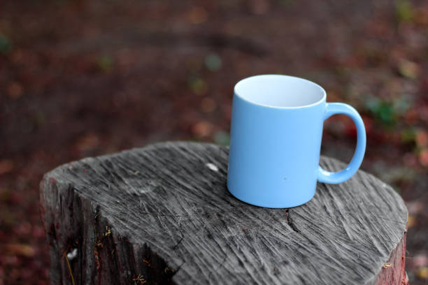 istock blue cup for coffee, placed on a log, autumn color 1150875544