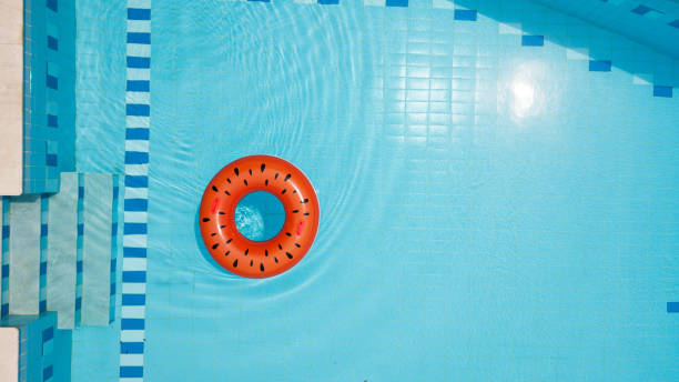 Watermelon inflatable ring floating in swimming pool Watermelon inflatable ring floating on water in empty swimming pool inner tube stock pictures, royalty-free photos & images