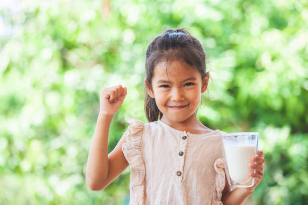 mignon asiatique enfant fille retenant le verre du lait et faire le geste fort - anger child furious asian ethnicity photos et images de collection