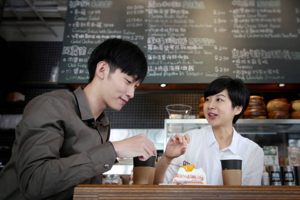 Two young adults spending leisure time chatting over a cup of coffee in cafe.