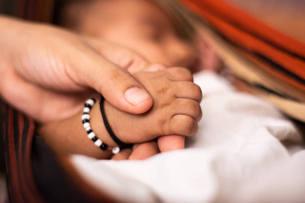 a newborn baby holding the parent hand while sleeping at cradle - baby mother newborn childbirth imagens e fotografias de stock