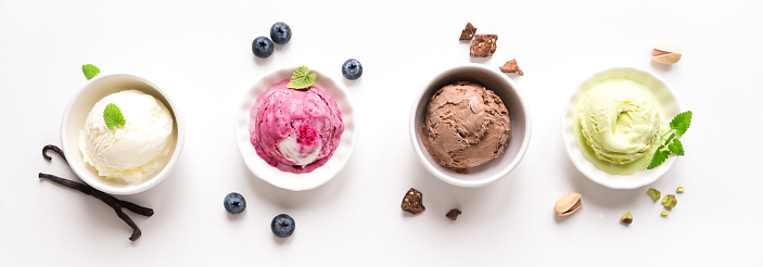 Ice Cream Assortment. Various ice creams and ingredients on white background, banner. Frozen yogurt or ice cream in cups - healthy summer dessert.