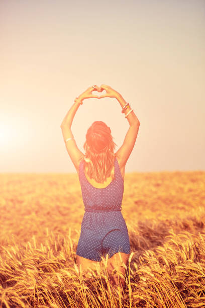 chica sosteniendo el símbolo de la forma del corazón para el amor en un campo de trigo. - heart shape loneliness women praying fotografías e imágenes de stock