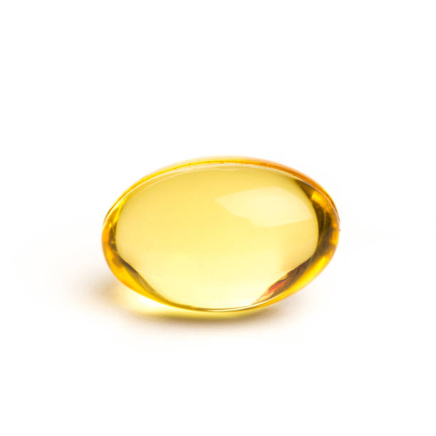 fermez vers le haut les suppléments d’huile de couleur dorée dans la capsule molle de gel, concept sain de produit-image - cod liver oil capsule vitamin pill vitamin e photos et images de collection