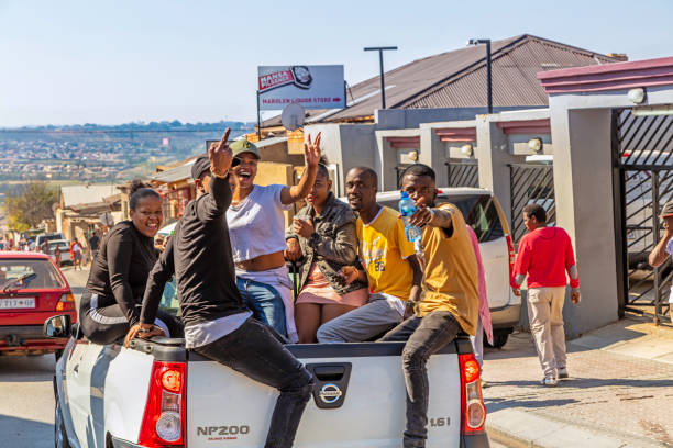 Young african people traveling on the back of a pick-up van in Alexandra Township Young african people traveling on the back of a pick-up van waving and smiling in Alexandra Township. Alexandra also known as Alex was developed since 1912 and allocated for the africans in the apartheid era, it is now home to over 400 000 inhabitants in an area 7,6 km2, and forms part of Johannesburg city council. alexandra township photos stock pictures, royalty-free photos & images