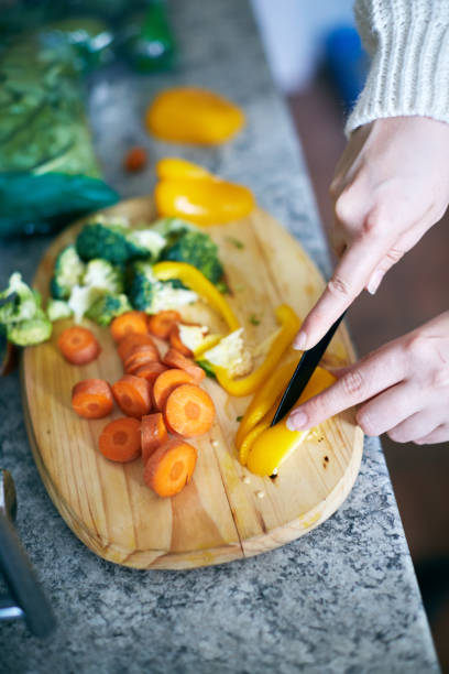 istock Looking down at female hands slicing raw vegetables 1150890819