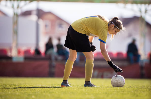 istock Female goalkeeper adjusting a ball on grass at stadium. 1150892498