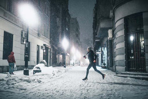 Woman jogging in winter night in the empty city streets