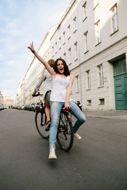 istock Friendship: two young women drive together on one bicycle 1150896758