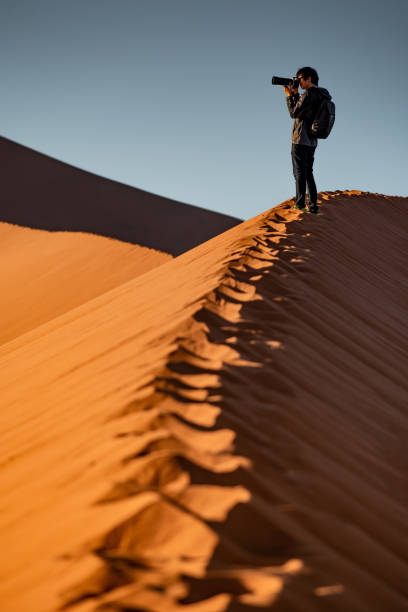 istock Male photographer standing on sand dune 1150898772