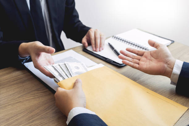 istock Cropped Hand Of Man Giving Bribe While Sitting At Desk 1150900202