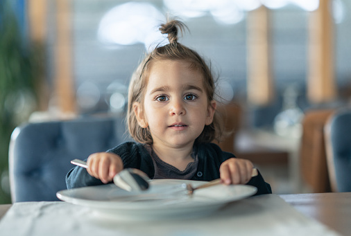 Little girl holding fork and spoon with