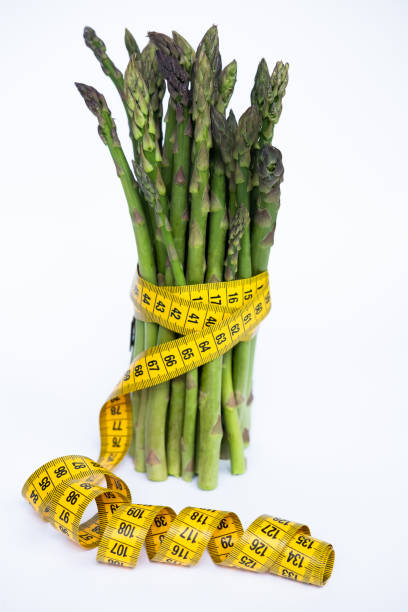 istock Fresh green asparagus bunch with measuring tape isolated over white background 1150905928