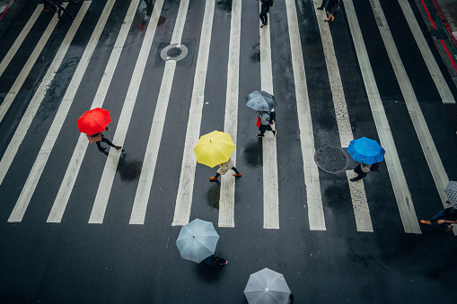 Group of people with umbrellas on the crosswalk, walking the street of Taipei on a rainy day.
