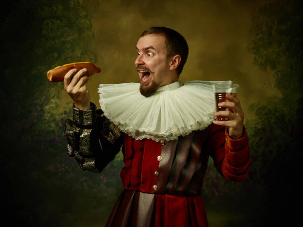 junger mann als mittelalterlicher ritter auf dunklem hintergrund - wearing hot dog costume stock-fotos und bilder