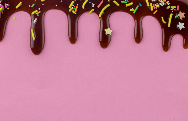 istock Cake topping coloured sprinkles with chocolate flowing down on pink background 1150909578
