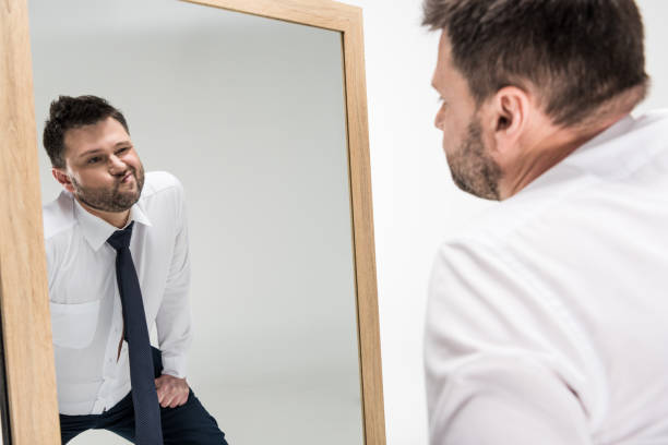 istock chubby man in formal wear looking at reflection in mirror isolated on white 1150909966
