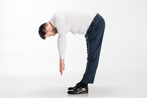overweight man in tight formal wear bending over and stretching on white