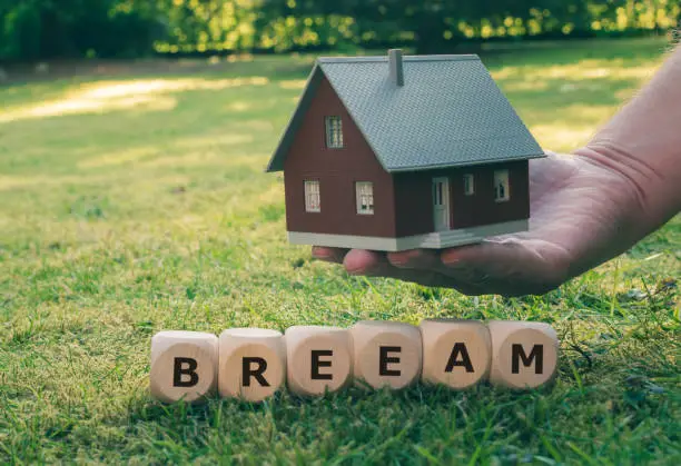 Photo of Cubes form the abbreviation BREEAM (Building Research Establishment Environmental Assessment Method) in front of a model house.