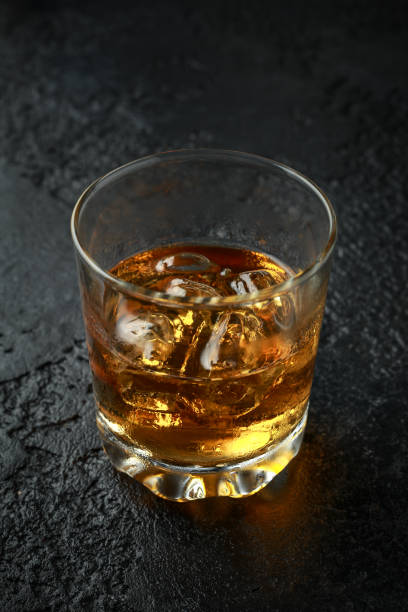istock Glass of whiskey with ice on rustic background 1150913768