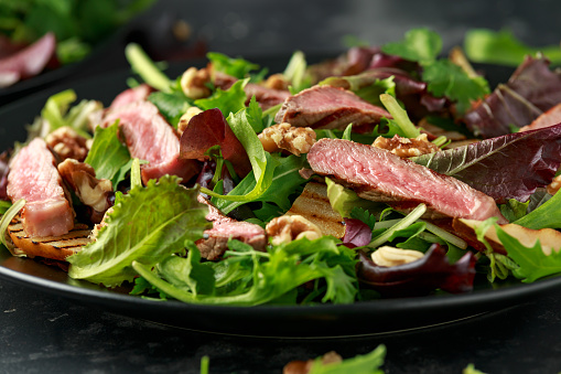 Grilled Beef Steak salad with pears, walnuts and greens vegetables and blue cheese sauce. healthy food