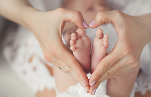 Mother’s hands holding new born baby’s feet