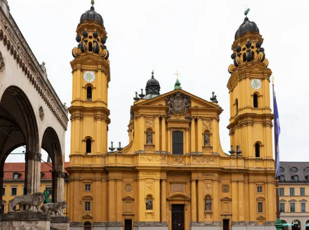 Public square close to Munich city centre surrounded by a yellow Catholic church and the Feldherrnhalle, monument to the Bavarian Army
