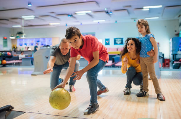 niño pequeño bowling con la familia - bolo fotografías e imágenes de stock