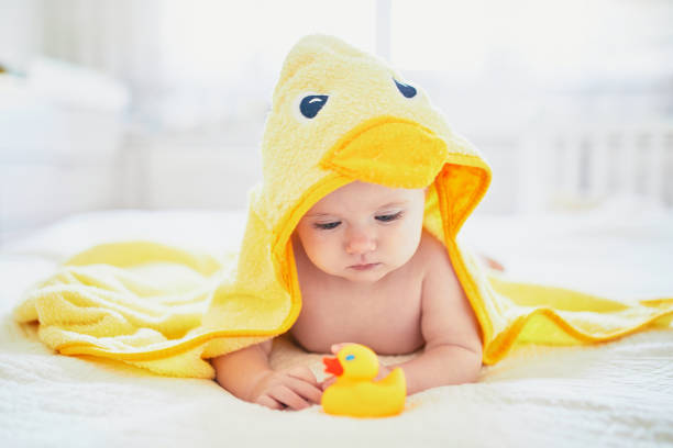 Cute little girl playing with rubber duck after having bath