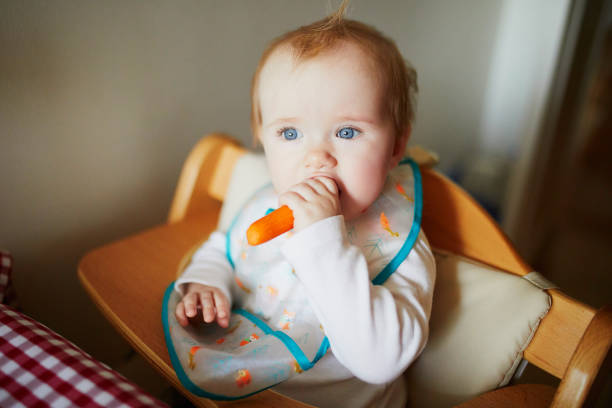 linda niña comiendo zanahoria en la cocina - baby carrot fotografías e imágenes de stock