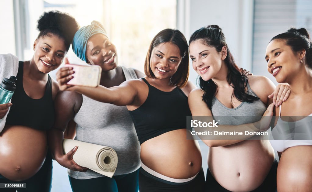 Pose for the camera ladies! Shot of a beautiful group of young pregnant women taking a selfie together after a yoga session in studio Pregnant Stock Photo