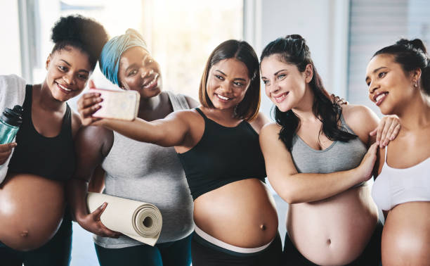 Pose for the camera ladies! Shot of a beautiful group of young pregnant women taking a selfie together after a yoga session in studio photo messaging stock pictures, royalty-free photos & images