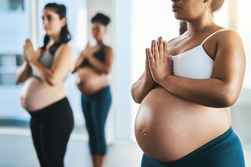 Shot of a group of young pregnant women meditating and practising yoga together in studio