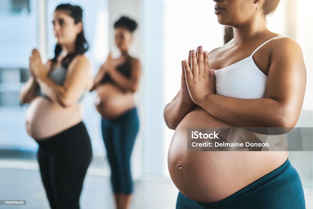 We need all the peace in this journey to motherhood Shot of a group of young pregnant women meditating and practising yoga together in studio Pregnant Stock Photo
