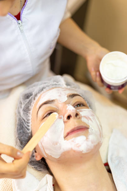 istock Cosmetologist applying mask on client's face, top view 1150920335