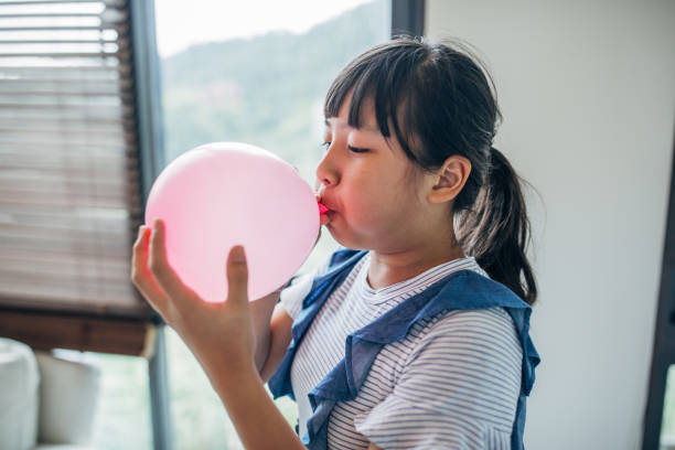 girl infla globos rosados - balloon blowing inflating child fotografías e imágenes de stock