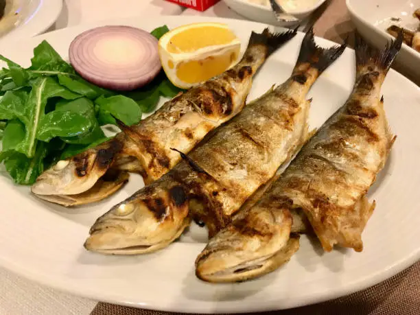 Chinese Fish Cinekop / Sarikanat Bluefish at Restaurant Served with Onions and Salad from Istanbul Turkey. Organic Food.