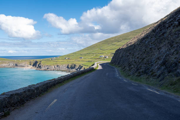 istock Looking along the empty winding road and rugged cliffs of the Dingle Peninsula, Ireland, bright blue sky with fluffy clouds 1150922967