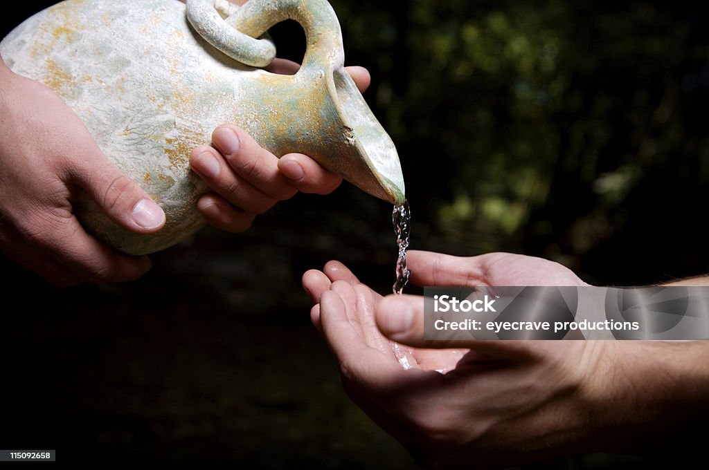 water poured out - humanitarian pouring fresh stream water out of a clay jug representing benevolent servanthood and humanitarian or christian service Altruism Stock Photo