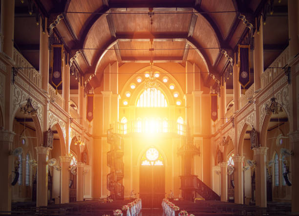vista interna della chiesa vuota con panca in legno decorata con bouquet di fiori, luce del sole attraverso la vetrata della chiesa - luogo di preghiera foto e immagini stock