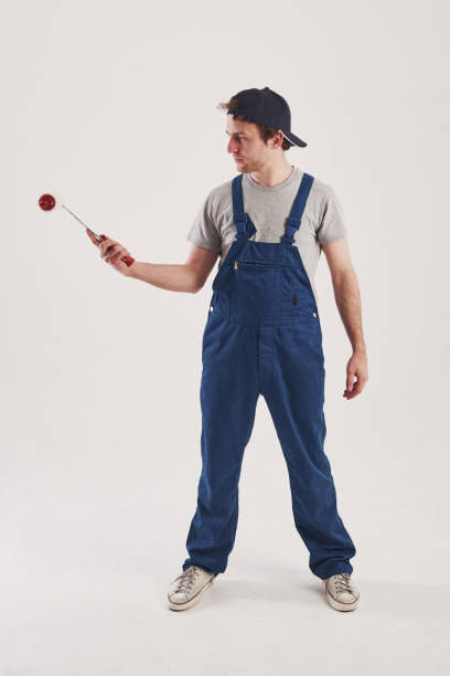 istock Red colored tool in hand. Man in blue uniform stands against white background in the studio 1150929289