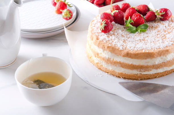 istock Setting the table during tea time.Fresh baked sponge cake with strawberry,green tea, plates, teapot 1150929772