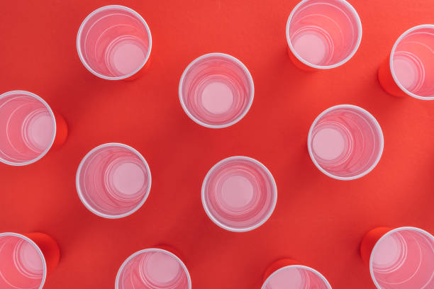 top view of bright and colorful plastic cups on red background