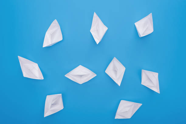 istock Top view of white paper boats on blue surface 1150934807