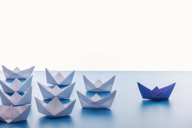 istock Paper boats on light blue surface on white background 1150934825