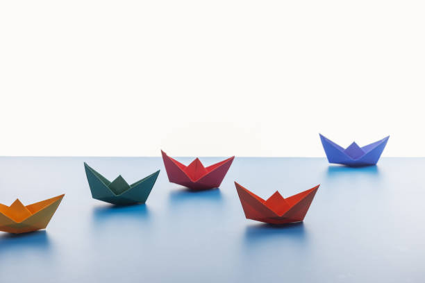 istock Colorful paper boats on light surface on white background 1150934862