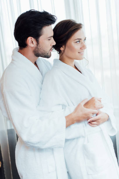 istock happy couple in white bathrobes hugging in hotel 1150936128