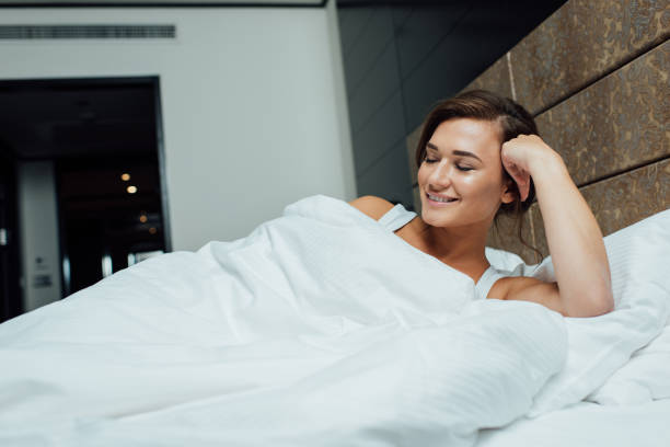 istock cheerful brunette woman smiling while lying on pillows with closed eyes 1150936183