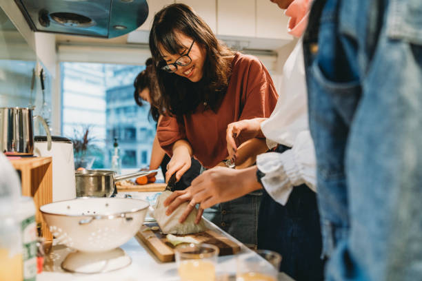 grupo de amigos que preparam o jantar junto na cozinha - foodie - fotografias e filmes do acervo