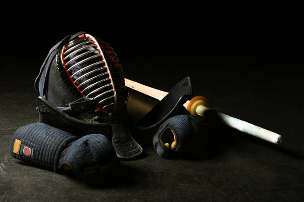 Kendo gloves, helmet and bamboo sword on dark surface